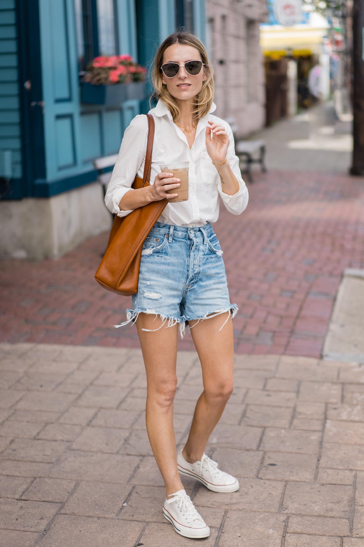 Jess Ann Kirby wears Agolde Dee Denim shorts with a classic white button down