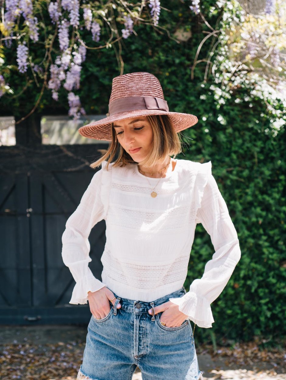 Jess Ann Kirby styles one of her favorite summer accessories, a straw hat, with classic denim shorts.