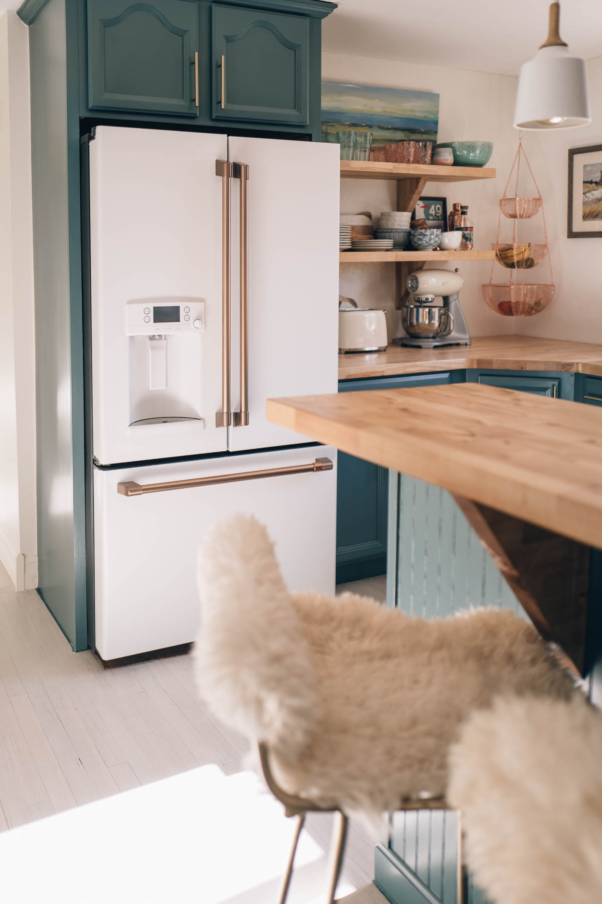 2019 kitchen design trends, warm hardware finishes and bold cabinetry colors in blue feauturing Cafe Appliances in Matte White with Brushed Bronze Hardware.