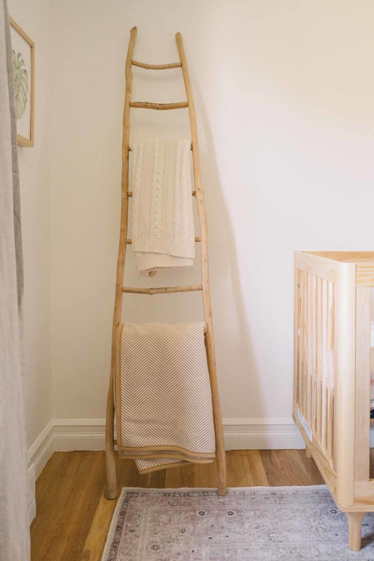 Jess Ann Kirby uses a wood latter to hang baby blankets in her gender neutral nursery.