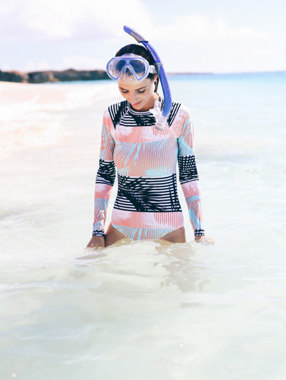 Jess Ann Kirby enjoys the tropics in a bright Roxy long sleeve swimsuit