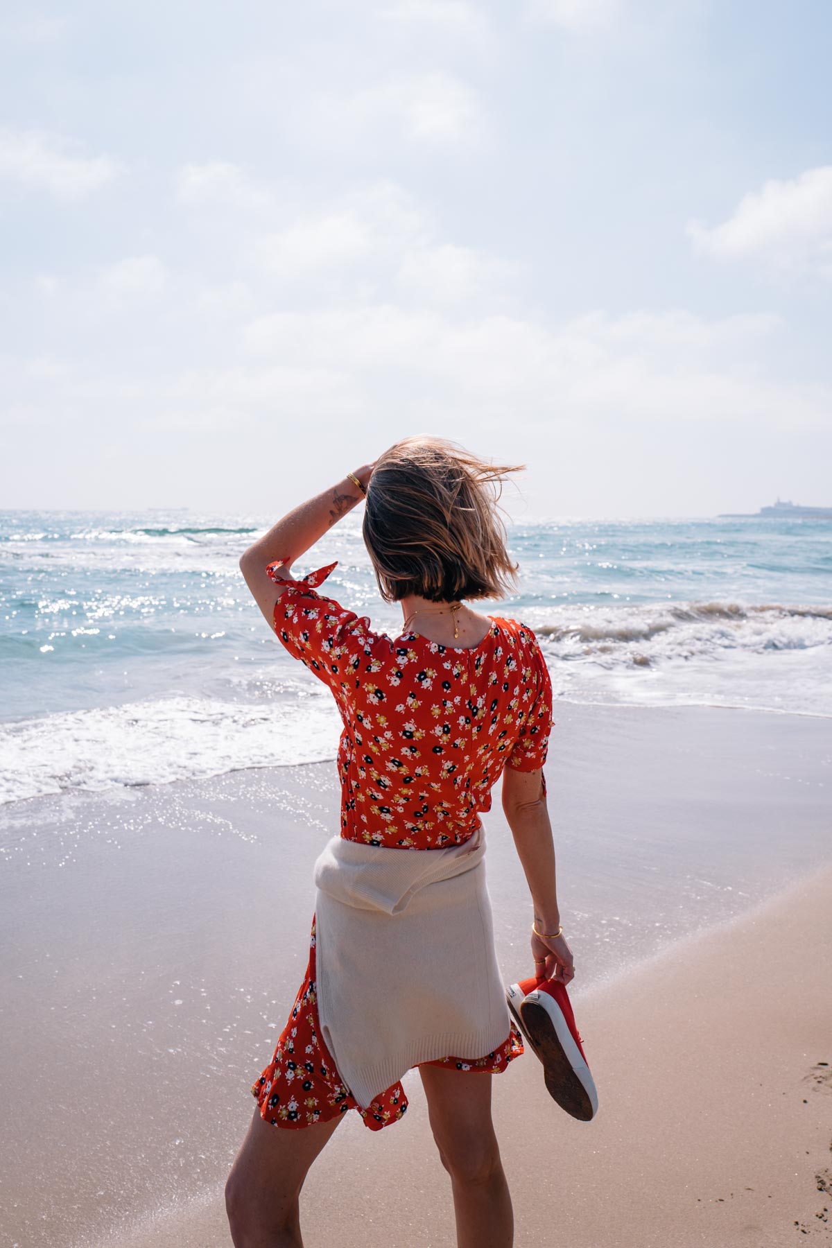 Jess Ann Kirby wears a printed red dress with sneakers for a cute and comfortable look while exploring the coast of Spain.